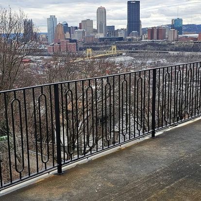 Custom ornamental wrought-iron railing with scrollwork, overlooking the downtown Pittsburgh skyline